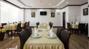 a dining room with tables and chairs and a tv at The Mou Hotel in Phnom Penh