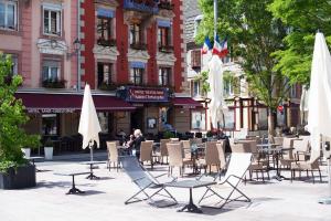 eine Gruppe von Stühlen, Tischen und Sonnenschirmen auf einer Stadtstraße in der Unterkunft Hotel-Restaurant St-Christophe in Belfort