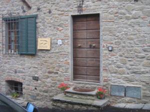 ein Steingebäude mit einer Holztür und einem Fenster in der Unterkunft Casa Velia in Uzzano