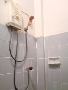 een douche met een slang in een wit betegelde badkamer bij OhoWowGood in Chiang Mai