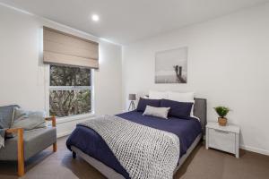 a bedroom with a bed and a chair and a window at Coastal Comfort, Just a Ocean Glimpse Away Torquay in Torquay