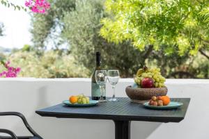 a table with a bottle of wine and a basket of fruit at Helios Beach Studios in Plaka