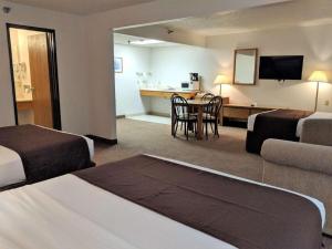 a hotel room with two beds and a table and a kitchen at Americas Best Value Inn Torrington in Torrington