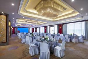 a banquet hall with white tables and white chairs at Feicheng Blossom Hotel in Feicheng