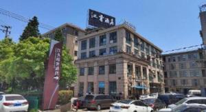 LuodianにあるJinjiang Inn Shanghai Baoshan Shengqiaoの駐車場に車が駐車されている大きな建物