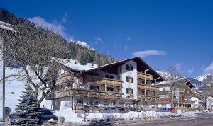 duży budynek na stronie pokrytej śniegiem góry w obiekcie Hotel Soreie w mieście Pozza di Fassa