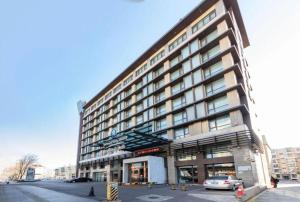 Un gran edificio con un coche aparcado delante. en Tianjin Juchuan Lily Hotel, en Binhai
