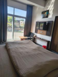 a hotel room with a large bed and a window at Shree Vallabh Resort in Nāthdwāra +53 photos