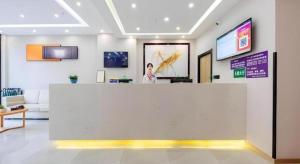 a woman standing behind a counter in a lobby at GreenTree Inn Ganzi Daochengzhou Scenic Area in Kanggar