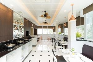a restaurant with white tables and chairs and windows at Empress Hotel Ho Chi Minh City in Ho Chi Minh City