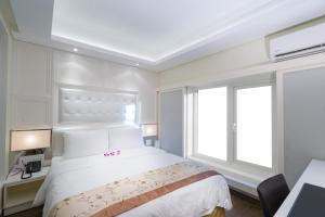 a bedroom with a white bed and a window at Empress Hotel Ho Chi Minh City in Ho Chi Minh City