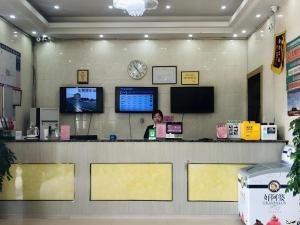 a woman sitting at a counter in a store at GreenTree Inn Heze Mudan Road Bus Terminal Station Express Hotel in Heze