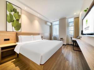 ein Hotelzimmer mit einem großen weißen Bett und einem Flachbild-TV in der Unterkunft GreenTree Inn HuZhou AnJi YingBin Avenue Express Hotel in Huangshu + 152 Fotos