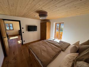 a bedroom with a bed and a flat screen tv at DAS BISCHOF - 5 exklusive Ferienwohnungen mit privaten Zirbensaunen - inkl Hindelang PLUS in Bad Hindelang