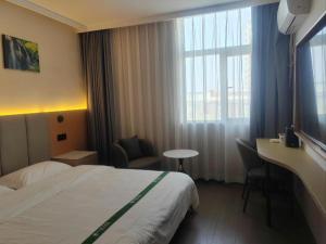 a hotel room with a bed and a desk and a window at GreenTree Inn Suzhou Wujiang Zhenze Town Zhennan Road Express Hotel in Suzhou