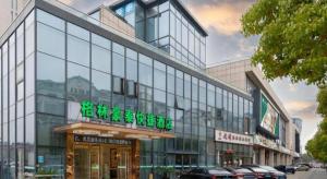 a large glass building with a sign on it at GreenTree Inn Suzhou Changshu North Haiyu Road Changhui Square Express Hotel in Changshu