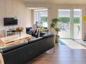 eine Familie sitzt in einem Wohnzimmer mit einem Sofa in der Unterkunft Luxury Pool Villa in Bagenkop - By Traum Ferienwohnungen in Bagenkop