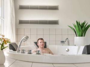 ein Mann in einer Badewanne in einem Badezimmer in der Unterkunft Luxury Pool Villa in Bagenkop - By Traum Ferienwohnungen in Bagenkop