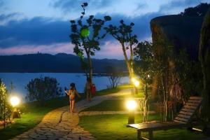 a woman walking down a path near a lake at night at Cô Tô Village in Ðiền Xá