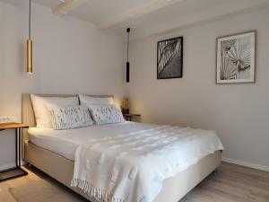a white bedroom with a large bed with white sheets at Charming Seaside House in Pag