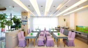 朝陽市にあるGreenTree Inn Chaoyang Shuangta District Bus Stationの紫色の椅子とテーブル、カウンターが備わるレストラン