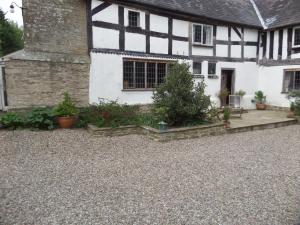 an old white and black house with a gravel driveway at Walford Court in Leintwardine