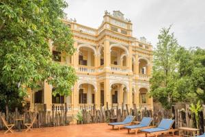a large yellow building with blue chairs in front of it at Le Relais de Chhlong in Chhlong