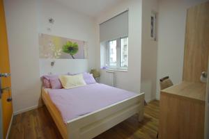 a bedroom with a bed with pink sheets and a window at Stella Di Notte in Belgrade