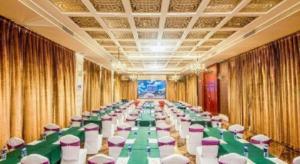PingzhouにあるFoshan Jubilee Hotelの緑のテーブルと椅子が置かれた長い宴会場