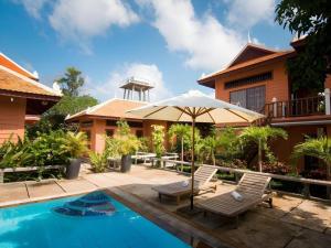 a patio with two chairs and an umbrella next to a house at Sambopich Chenla Hotel in Phumĭ Achary Leăk