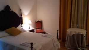 ein Schlafzimmer mit einem Bett, einem Tisch und einem Stuhl in der Unterkunft Solar Dos Viscondes - Turismo De Habitacao in Ferreira do Alentejo