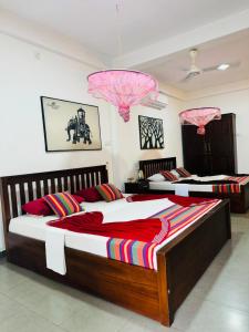 two beds in a bedroom with pink chandeliers at Tikla safari lodge in Udawalawe