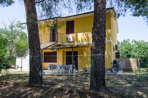 une maison jaune avec deux arbres devant elle dans l'établissement Agriturismo La Fragolaia, à Marina di Grosseto