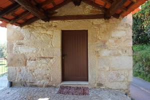 a stone building with a brown door and a rug at Casinha Pousafoles in Arouca