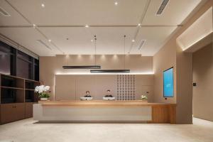 zwei Personen sitzen an einem Rezeptionstresen in einer Lobby in der Unterkunft Atour Hotel Chengdu High-Tech Zone in Chengdu