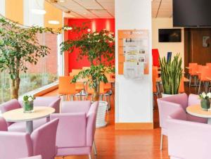 a restaurant with purple chairs and tables and plants at Ibis Chengdu Yongfeng Hotel in Chengdu