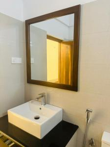 a bathroom with a white sink and a mirror at Tikla safari lodge in Udawalawe