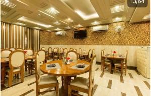 a restaurant with wooden tables and chairs and a tv at Hotel De Rosewood Inn -Near Delhi Airport-Free Airport Drop in New Delhi
