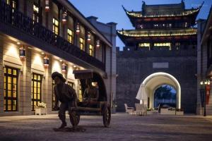 a statue of a man in a cart in front of a building at Atour Hotel Nantong Langshan Scenic Area in Yongxingzhen