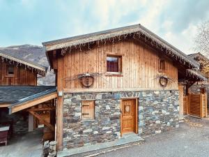 eine Blockhütte mit Steinfassade und Holztüren in der Unterkunft Cosy 4 bedroom chalet with hot tub (Chalet Velours) in Saint-Marcel