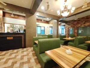 a restaurant with green chairs and tables and a chandelier at Great Samrat Residency in Khopoli