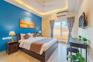坎多林Lush View 2BHK Apartments in Candolim的一间有蓝色墙壁的卧室，里面有一张床和一张书桌