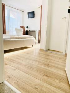 1 dormitorio con suelo de madera, 1 cama y TV en Oana Boutique C D I, en Bran