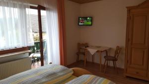 a bedroom with a bed and a table and a television at Pension Waldblick in Bayerisch Eisenstein