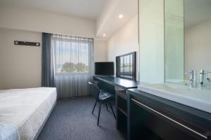 una habitación de hotel con una cama y un lavabo en Hotel Vista Kumamoto Airport, en Ozu