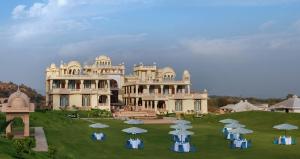 a large building with tables and umbrellas in front of it at Rajasthali Resort & Spa in Jaipur