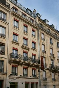 パリにあるHotel Riviera Renovatedの赤い窓とバルコニーが備わる大きな日焼けの建物