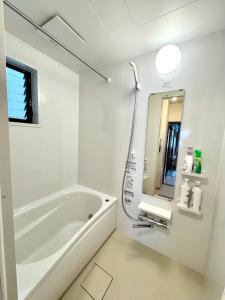 a white bathroom with a tub and a mirror at 横浜中華街,元町,山手エリア観光に最適,静かで62平米快適な一軒家,鎌倉へも好アクセス! in Yokohama +46 photos