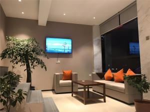 Una sala de estar con un sofá y un televisor en la pared. en Jtour Inn Suizhou Yanhe Avenue, en Suizhou