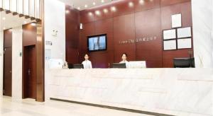 two women standing at a counter in a lobby at City Comfort Inn Yunfu Luoding Triumph Plaza in Shuangdongjieban